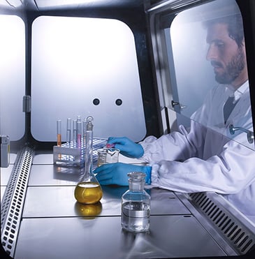 scientist working with beakers and bottles in a recirculating fume cabinet