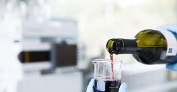 red win being poured into a beaker in a laboratory testing wine for heat and cold stability